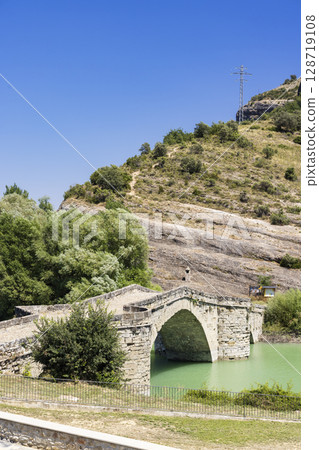 Medieval bridge crossing the Esera River in Graus, Huesca, Spain, under blue sky 128719108