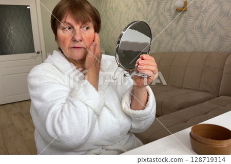 A refined senior lady is at her residence, carefully applying her makeup. A refined senior lady is at her residence, carefully applying her makeup. 128719314