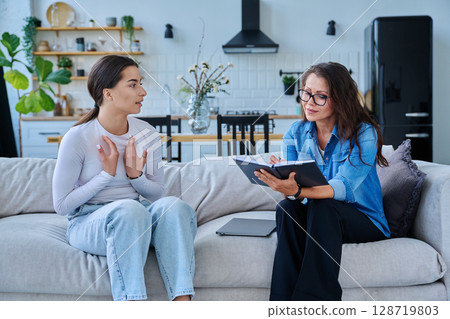 Female social worker working at home with teenage girl Female social worker working at home with teenage girl 128719803