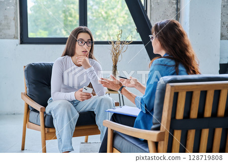 Serious teen girl in session in office of professional psychologist, therapist 128719808