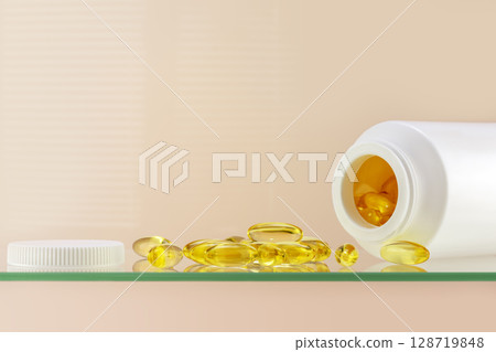 Omega 3. Health care composition with natural vitamins D3 on glass shelf on pink background with copy space. White bottle with healthy supplements in gel capsules. Natural vitamins and nutrients 128719848