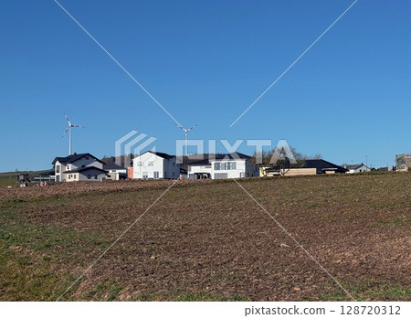 Houses with solar panels on roof and wind turbines nearby. Summer landscape with green vineyard. Eco energy concept 128720312