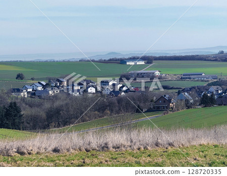 Wind turbines for renewable electricity, village houses and yellow rapeseed field Wind turbines for renewable electricity, village houses and yellow rapeseed field 128720335