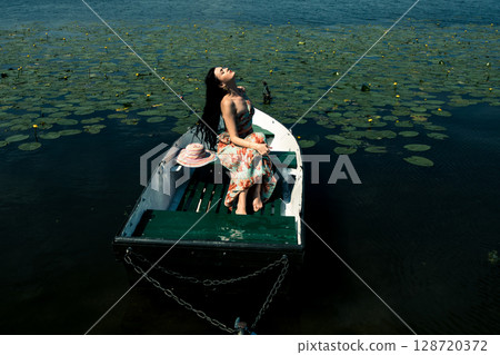The girl is sitting in a boat on the lake 128720372