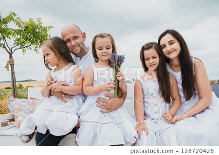 A happy mother and father gently embrace their daughters A happy mother and father gently embrace their daughters 128720428