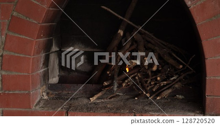 Outdoor brick oven with stacked firewood ready for cooking in a backyard setting during late afternoon hours offering a rustic and traditional cooking experience 128720520