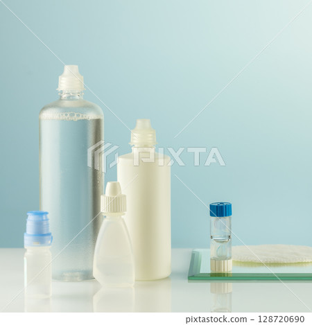 Ophthalmology concept with container with contact lenses, moisturizing eye drops and bottles with clean solution. Night contact lenses. Advertising contact lenses for vision. Optical store and eye car Ophthalmology concept with container with contact lenses, moisturizing eye drops and bottles with clean solution. Night contact lenses. Advertising contact lenses for vision. Optical store and eye car 128720690