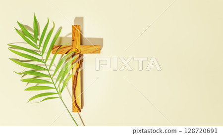 Palm Sunday Holiday. Wooden cross with palm leaf on light background with copy space. Religion background suitable for faith religion, christian holidays, Easter, Redeemer, the Feast of Corpus Christi Palm Sunday Holiday. Wooden cross with palm leaf on light background with copy space. Religion background suitable for faith religion, christian holidays, Easter, Redeemer, the Feast of Corpus Christi 128720691