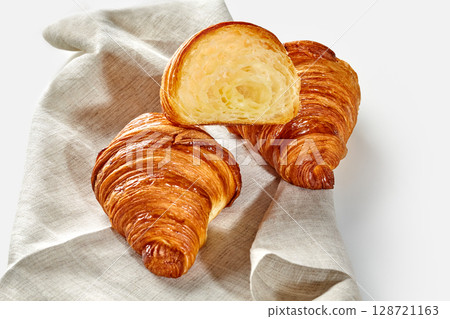 Delicious golden brown croissants resting on linen napkin: freshly baked pastry Delicious golden brown croissants resting on linen napkin: freshly baked pastry 128721163