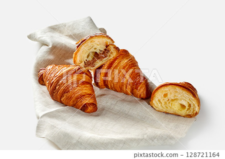 Delicious croissants with chocolate filling resting on linen napkin Delicious croissants with chocolate filling resting on linen napkin 128721164