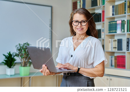 Portrait mature woman teacher, educational behavioral specialist with laptop in classroom 128721521