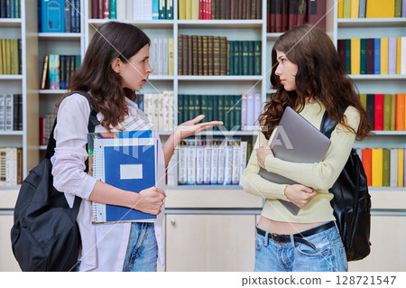 Two teenage students classmates chatting standing in classroom library 128721547