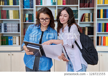 Teenage student girl meeting discussing with teacher mentor in classroom Teenage student girl meeting discussing with teacher mentor in classroom 128721555