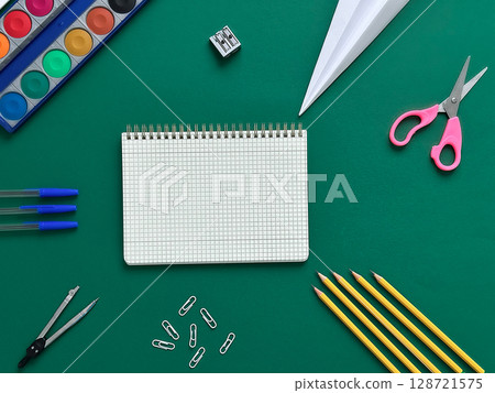 A textured background featuring school supplies. Items include a notebook, colored pencils, scissors, paper clips, A textured background featuring school supplies. Items include a notebook, colored pencils, scissors, paper clips, 128721575