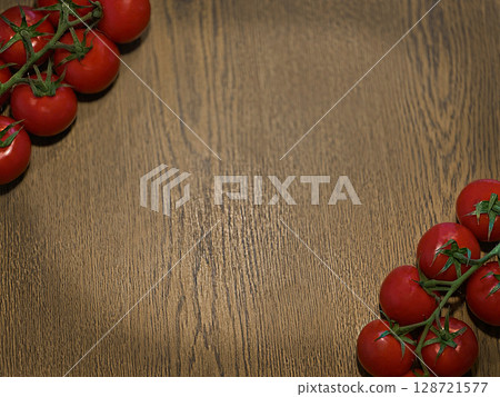Red tomatoes arranged on a wooden table background. The scene features fresh, ripe tomatoes with green stems, creating a vibrant  128721577
