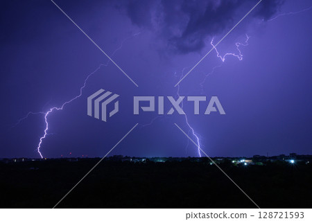 Multiple lightning bolts striking during dramatic night thunderstorm. Multiple lightning bolts striking during dramatic night thunderstorm. 128721593