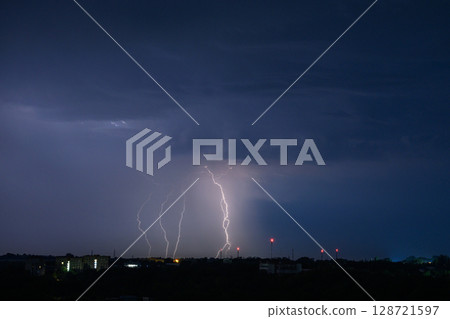 Multiple lightning bolts striking during dramatic night thunderstorm. 128721597