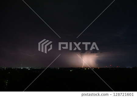 Lightning bolts and storm clouds over city during night. Lightning bolts and storm clouds over city during night. 128721601