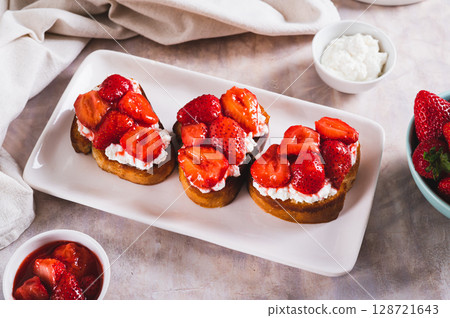 Sandwiches with cream cheese and fried strawberries on a plate on a table Sandwiches with cream cheese and fried strawberries on a plate on a table 128721643