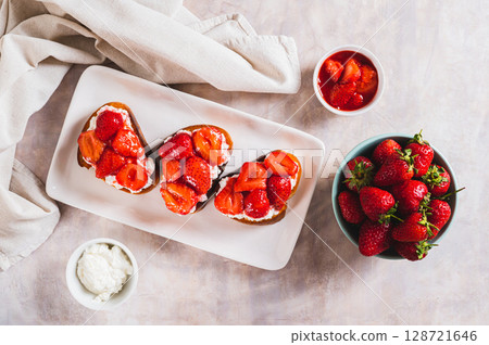 Appetizing bruschetta with ricotta and stewed strawberries on a plate top view 128721646