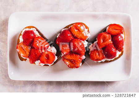 Close up of bruschettas with ricotta and stewed strawberries on a plate top view Close up of bruschettas with ricotta and stewed strawberries on a plate top view 128721647