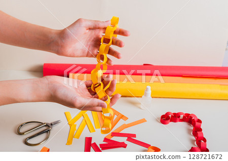 Handmade paper chain on women's palms and items for its production Handmade paper chain on women's palms and items for its production 128721672