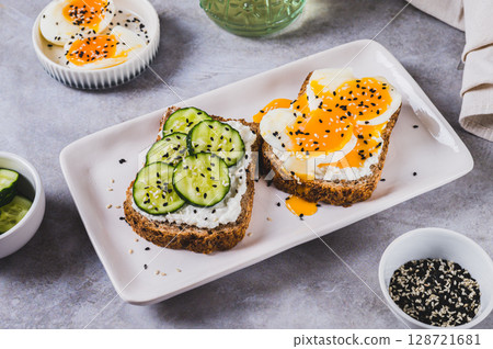 Cereal bread with cottage cheese, boiled egg and cucumber on a plate on the table Cereal bread with cottage cheese, boiled egg and cucumber on a plate on the table 128721681