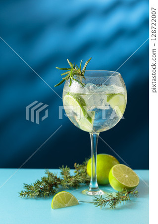 Cocktails gin and tonic with ice and lime slices on a blue background. 128722007