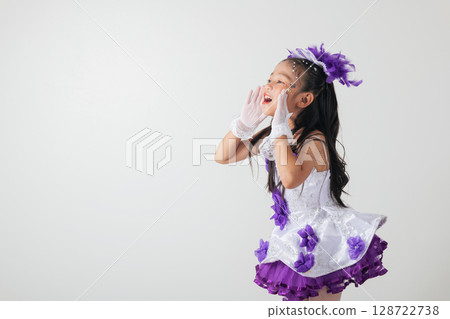 Cheerleader girl in a purple and white costume, shouting loudly with her hands cupped around her mouth. Wearing white gloves and purple accents, her expression is energetic and dramatic. isolated 128722738
