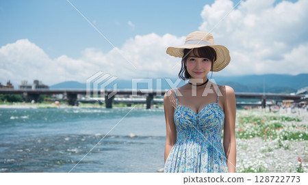A woman wearing a straw hat and a dress on a riverbank in midsummer A woman wearing a straw hat and a dress on a riverbank in midsummer 128722773