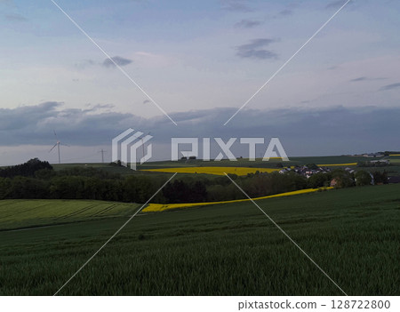 Wind turbine towers in a green field under the blue sky generating alternative energy for sustainable growth Wind turbine towers in a green field under the blue sky generating alternative energy for sustainable growth 128722800