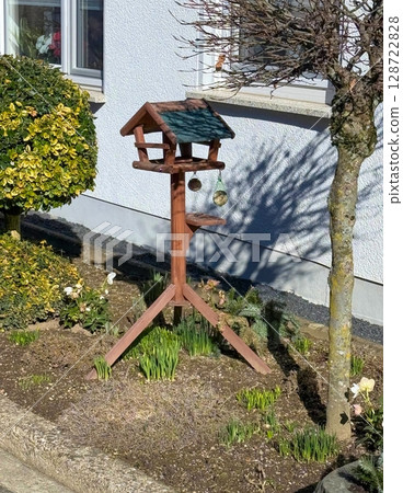 Birdhouse in Sunlit Garden with Empty Feeders 128722828