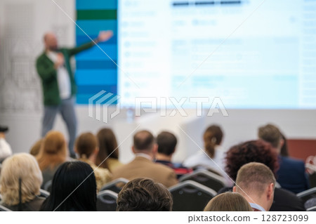 Audience watching a presenter speaking at a professional business conference Audience watching a presenter speaking at a professional business conference 128723099