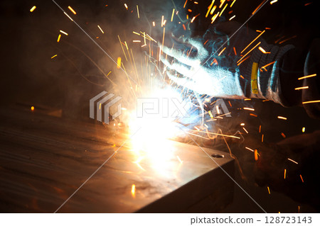 Welder uses torch to make sparks during manufacture of metal equipment, industrial professional worker Welder uses torch to make sparks during manufacture of metal equipment, industrial professional worker 128723143