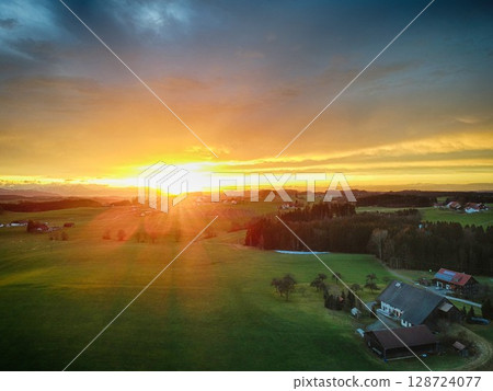 Beautiful sunset over a field with a house in the distance 128724077
