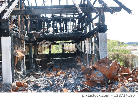 A burned down building with a lot of debris and a lot of smoke 128724180