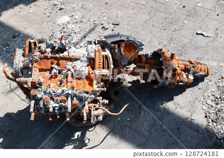 A rusted engine is on the ground, with a lot of debris around it A rusted engine is on the ground, with a lot of debris around it 128724181