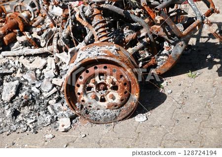 A car is in a junkyard with a wheel that is burnt and rusted A car is in a junkyard with a wheel that is burnt and rusted 128724194
