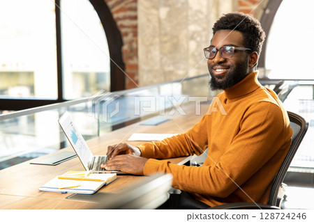 African american young man with laptop working in the office African american young man with laptop working in the office 128724246