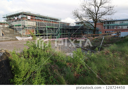 A building is being demolished and the area is overgrown with weeds 128724450