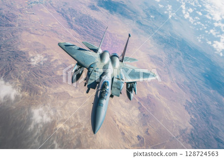 A military fighter jet soars over rugged desert terrain with powerful wings and visible missiles, highlighting airforce strength and aviation dominance A military fighter jet soars over rugged desert terrain with powerful wings and visible missiles, highlighting airforce strength and aviation dominance 128724563