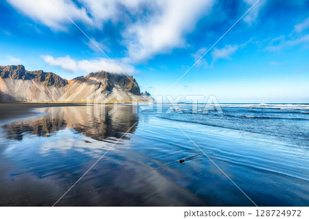 Amazing sunny day and dramatic black sand beach on Stokksnes cape in Iceland Amazing sunny day and dramatic black sand beach on Stokksnes cape in Iceland 128724972