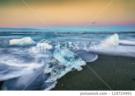 Ramarkable pieces of the iceberg sparkle on famous Diamond Beach at  Jokulsarlon lagoon during sunset. 128724991