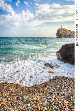 Amazing view of sea waves crashing on the shore and flowing above seashore pebbles. Amazing view of sea waves crashing on the shore and flowing above seashore pebbles. 128724996