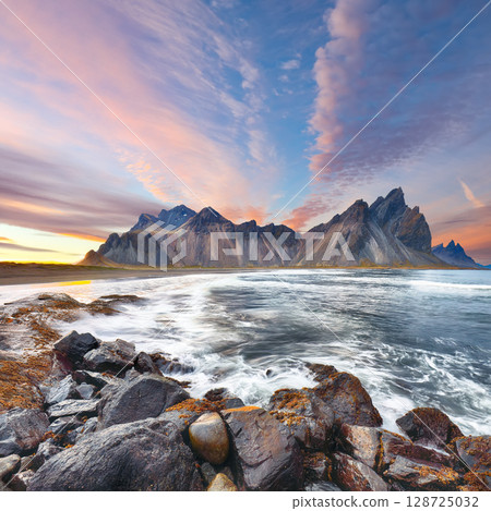 Remarkable sunset with gorgeous black sand dunes on Stokksnes cape in Iceland. 128725032