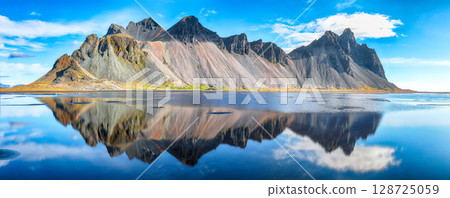 Amazing sunny day and gorgeous reflection of Vestrahorn mountaine on Stokksnes cape in Iceland. Amazing sunny day and gorgeous reflection of Vestrahorn mountaine on Stokksnes cape in Iceland. 128725059