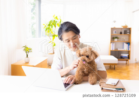 Telework: A man working while holding a dog 128725109