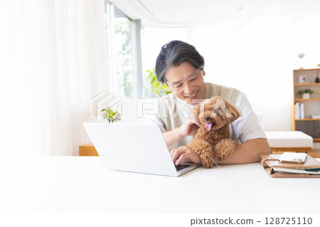 Telework: A man working while holding a dog 128725110
