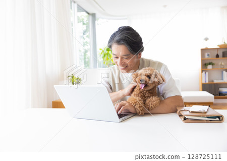 Telework: A man working while holding a dog 128725111