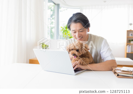 Telework: A man working while holding a dog Telework: A man working while holding a dog 128725113